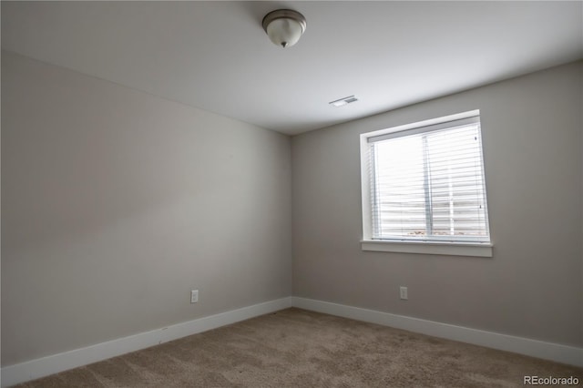 unfurnished room with carpet, visible vents, and baseboards