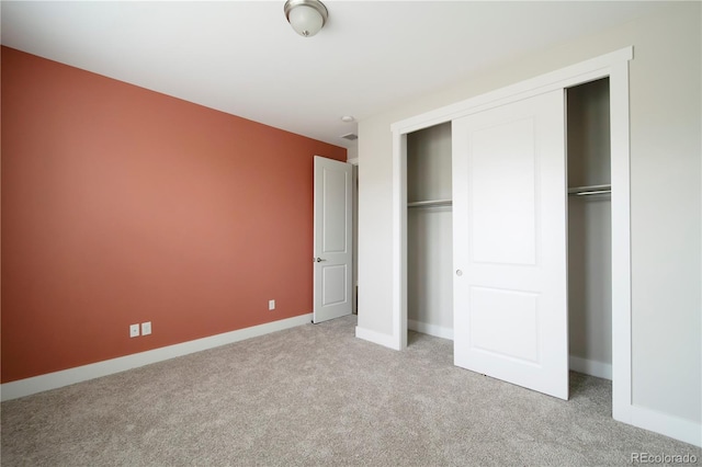 unfurnished bedroom with baseboards, light carpet, and a closet
