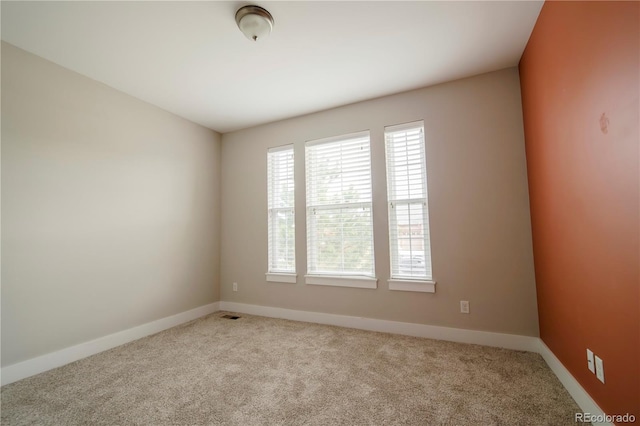 carpeted empty room featuring baseboards and visible vents