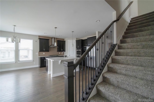 staircase with recessed lighting, baseboards, a notable chandelier, and wood finished floors