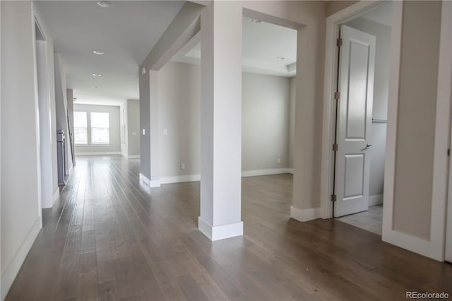 corridor with baseboards and dark wood-style floors