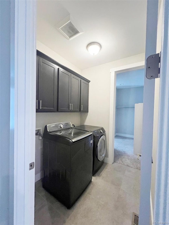 laundry room with washing machine and dryer, cabinet space, and visible vents