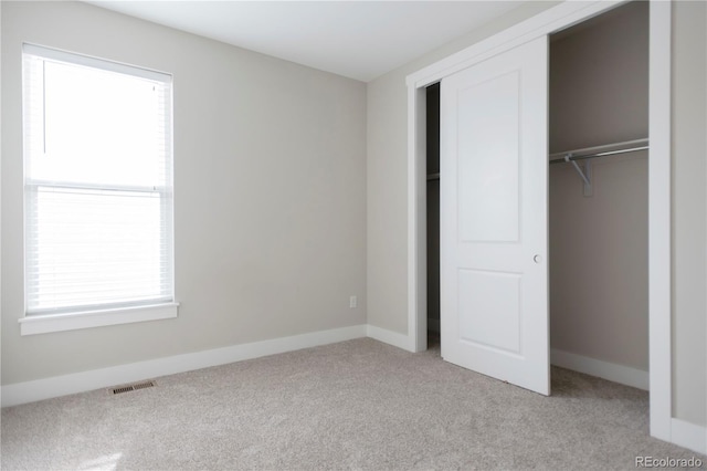 unfurnished bedroom featuring visible vents, carpet flooring, multiple windows, and a closet