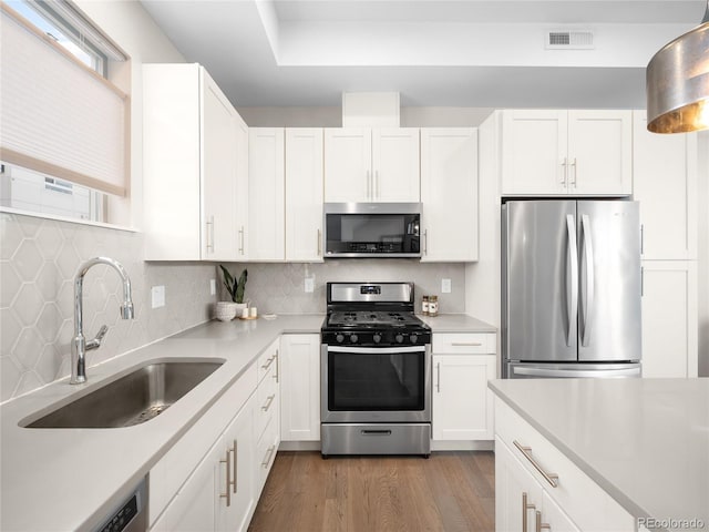 kitchen with sink, dark hardwood / wood-style flooring, stainless steel appliances, decorative backsplash, and white cabinets