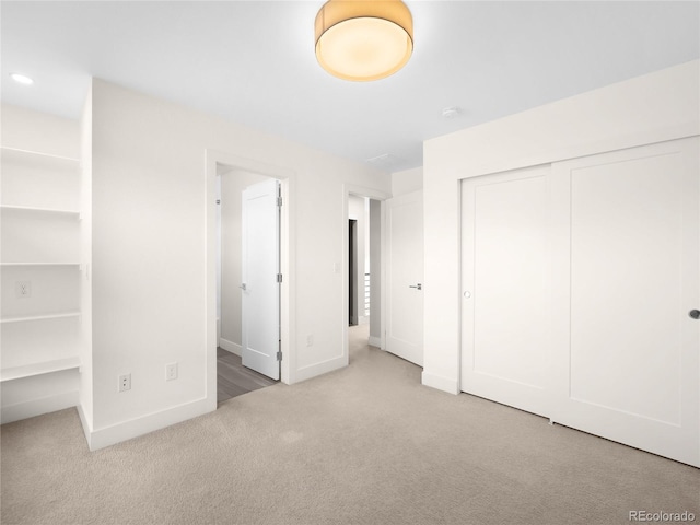 unfurnished bedroom with light colored carpet and a closet