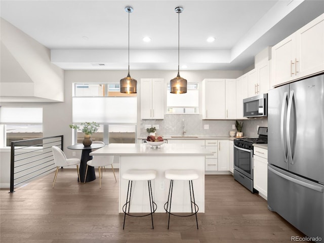 kitchen with a sink, stainless steel appliances, a breakfast bar, decorative backsplash, and a kitchen island