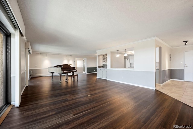 living area with a textured ceiling, wood finished floors, baseboards, and ornamental molding