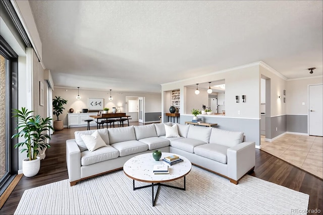 living room featuring light wood-type flooring, ornamental molding, and a textured ceiling