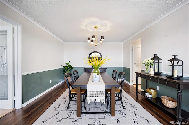 dining area featuring wood finished floors, a chandelier, ornamental molding, baseboards, and a textured ceiling