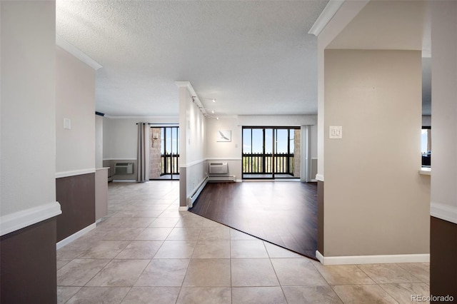 corridor with a wall mounted air conditioner, a textured ceiling, light tile patterned floors, baseboards, and ornamental molding