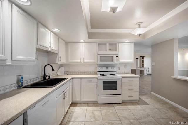 kitchen featuring a sink, white appliances, light countertops, white cabinets, and a tray ceiling