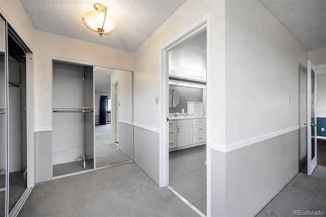 interior space with a closet, a textured ceiling, ensuite bathroom, and carpet