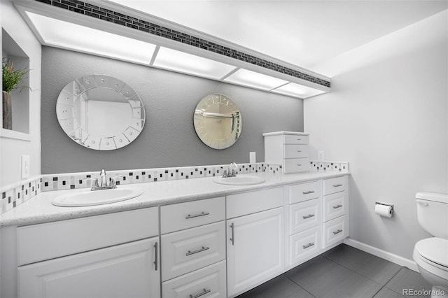 bathroom with a sink, double vanity, toilet, and tile patterned floors
