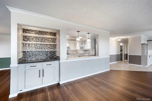 indoor bar featuring white appliances, crown molding, a textured ceiling, backsplash, and dark wood-style flooring