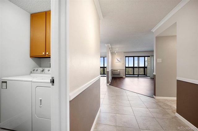 corridor featuring washing machine and clothes dryer, a textured ceiling, baseboards, and light tile patterned floors