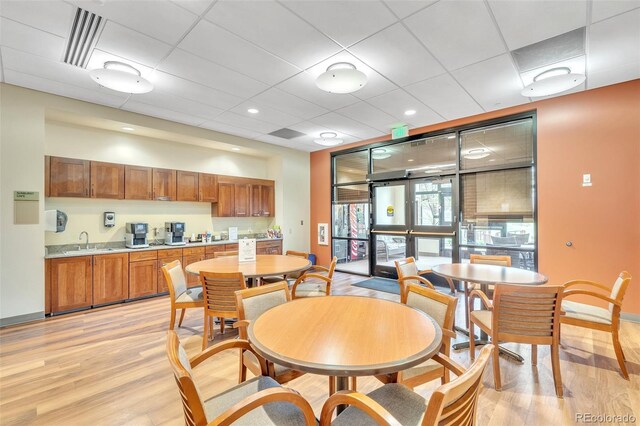 dining room featuring light wood-style flooring, baseboards, and a paneled ceiling