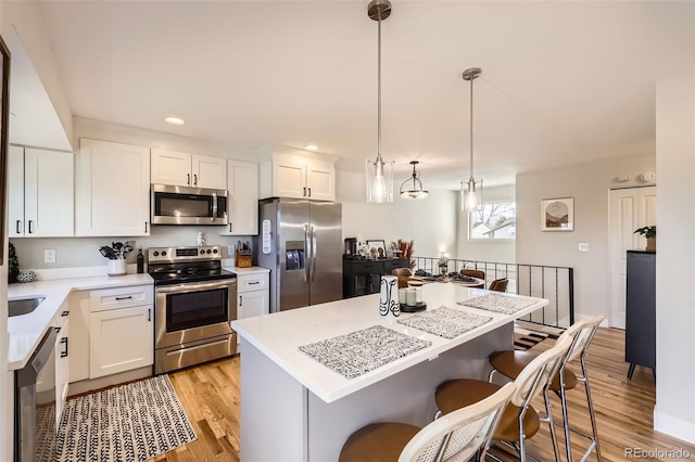 kitchen with decorative light fixtures, white cabinetry, and appliances with stainless steel finishes