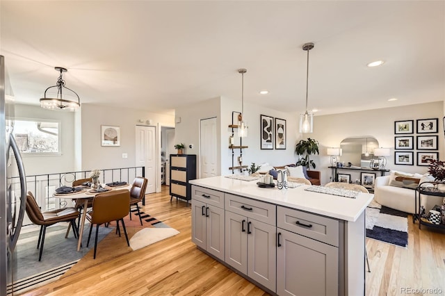 kitchen with hanging light fixtures, light wood-type flooring, gray cabinetry, and a kitchen island