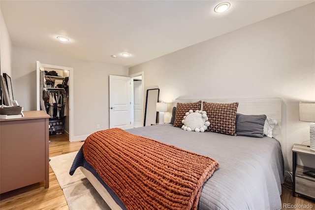 bedroom with a spacious closet, light hardwood / wood-style floors, and a closet