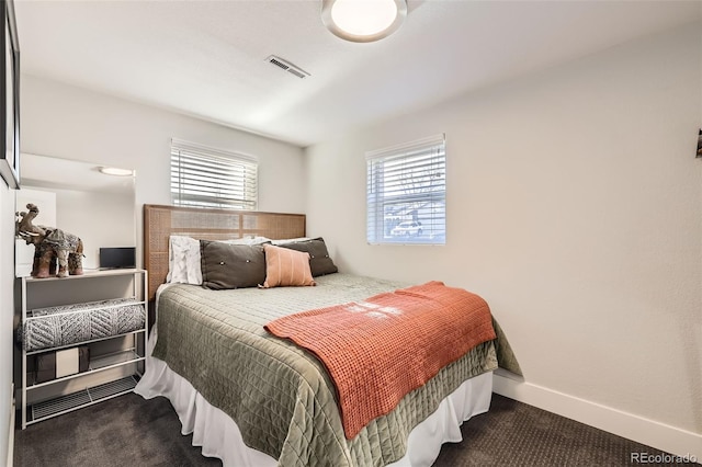 bedroom with multiple windows and dark colored carpet