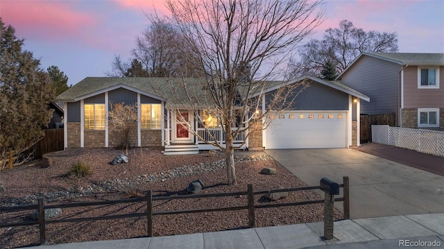 view of front of house with a fenced front yard, covered porch, a garage, stone siding, and driveway