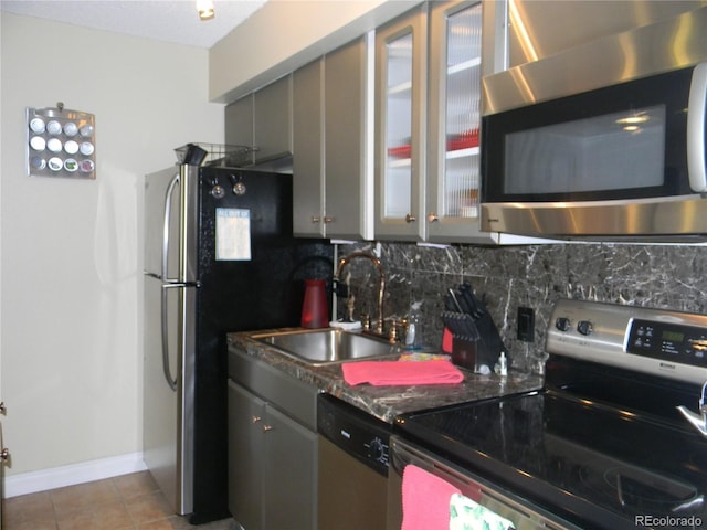 kitchen featuring gray cabinetry, sink, backsplash, light tile patterned flooring, and appliances with stainless steel finishes