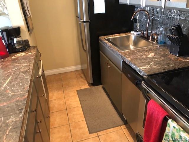 kitchen featuring tasteful backsplash, sink, light tile patterned floors, and appliances with stainless steel finishes