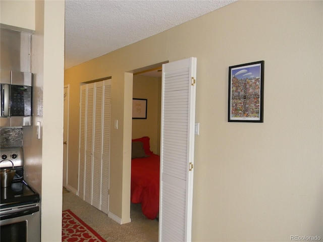 corridor featuring a textured ceiling and light carpet