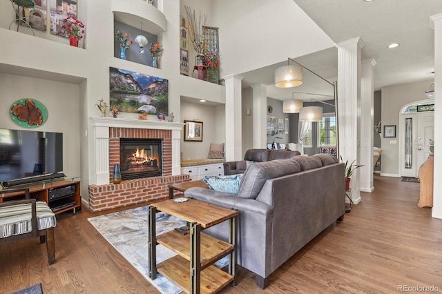 3973 Palmer Ridge Dr, Parker, CO 80134 - living room featuring wood finished floors, a fireplace, and ornate columns