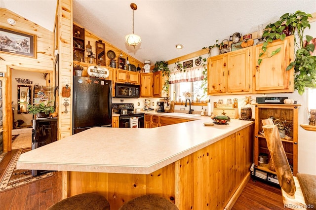 kitchen with pendant lighting, kitchen peninsula, vaulted ceiling, and black appliances