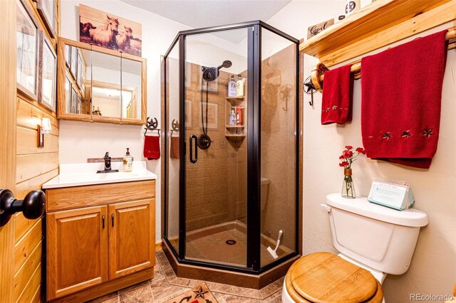 bathroom featuring a shower with door, vanity, and toilet