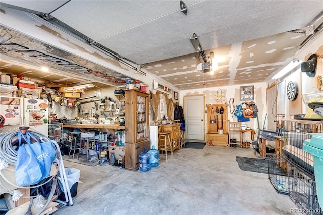 garage with white refrigerator, a garage door opener, and a workshop area