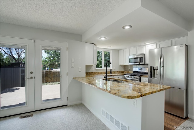 5163 E 123rd Ct, Thornton, CO 80241 - kitchen with appliances with stainless steel finishes, a peninsula, light stone counters, white cabinetry, and recessed lighting