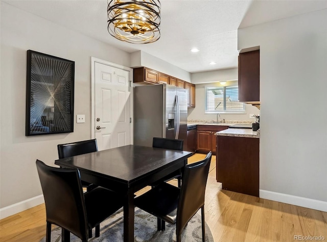 dining space with light hardwood / wood-style floors, a notable chandelier, and sink