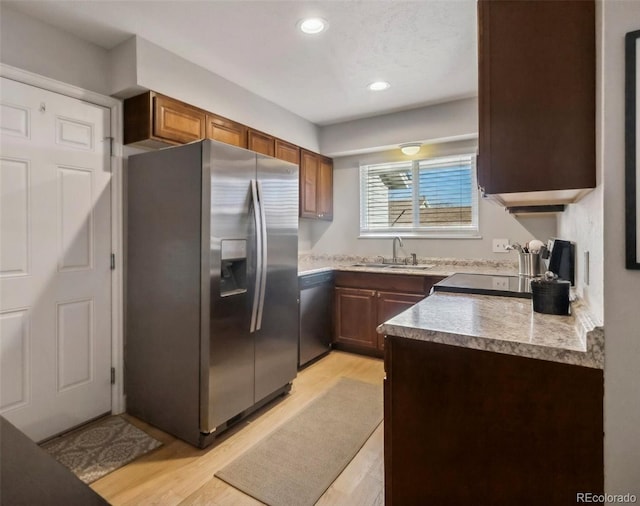 kitchen featuring dishwasher, sink, stainless steel refrigerator with ice dispenser, stove, and light hardwood / wood-style floors