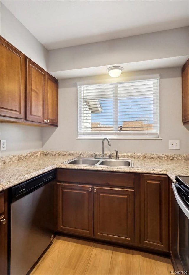 kitchen featuring dishwasher, sink, light stone counters, stove, and light wood-type flooring