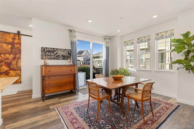 dining space featuring a barn door and dark hardwood / wood-style floors