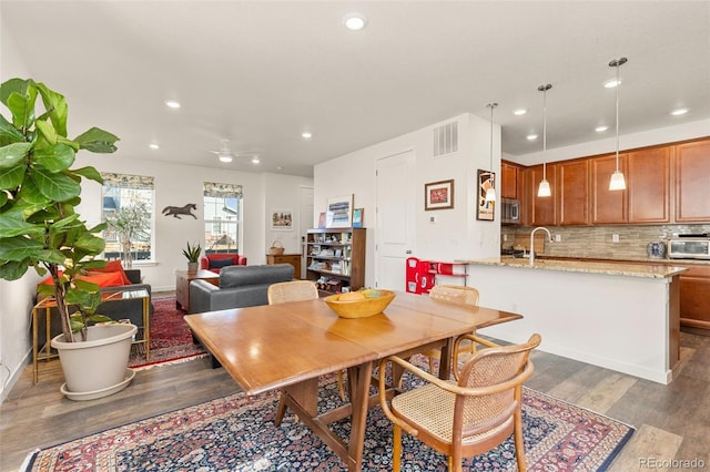 dining space with ceiling fan, sink, and dark wood-type flooring