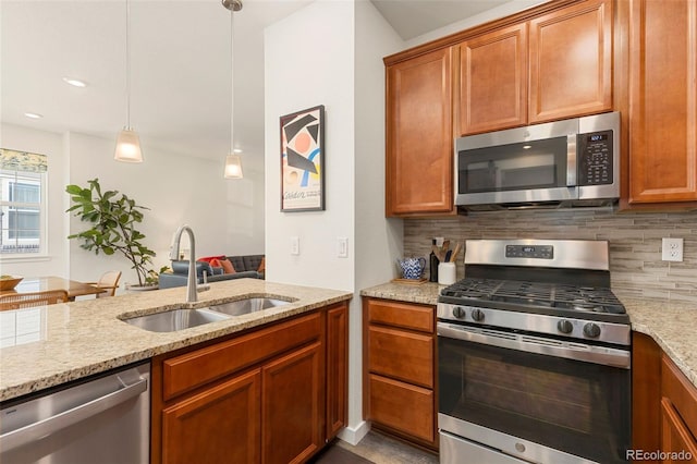 kitchen featuring light stone countertops, appliances with stainless steel finishes, backsplash, sink, and decorative light fixtures