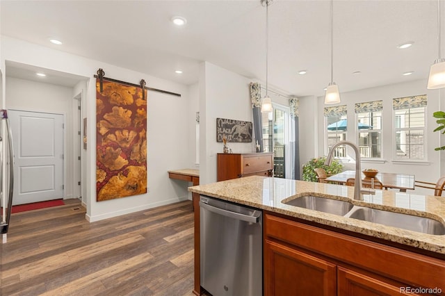 kitchen featuring dishwasher, sink, hanging light fixtures, a barn door, and dark hardwood / wood-style flooring