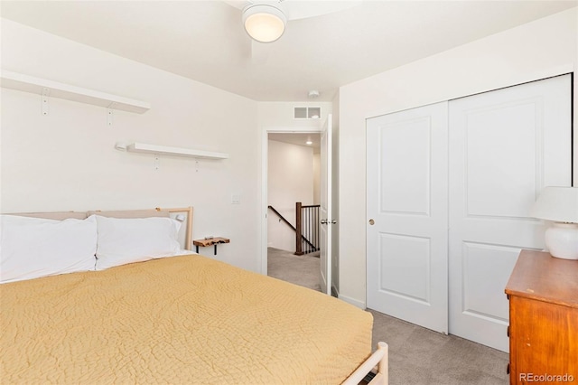 bedroom with ceiling fan, light carpet, and a closet