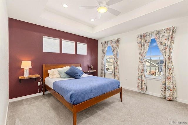 bedroom featuring a tray ceiling, ceiling fan, and light carpet