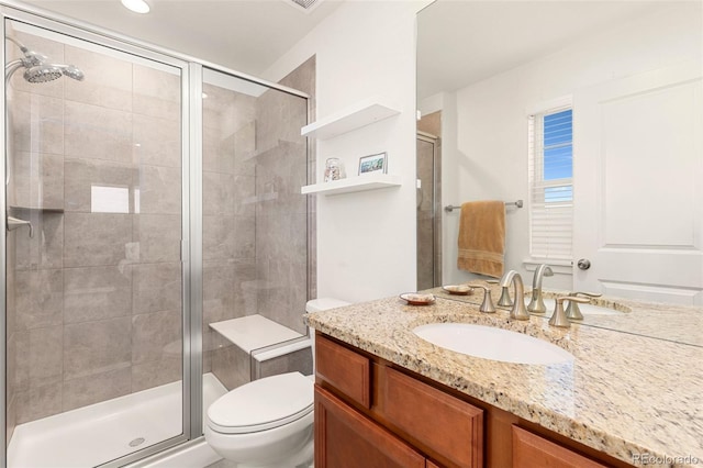 bathroom featuring vanity, toilet, and a shower with shower door