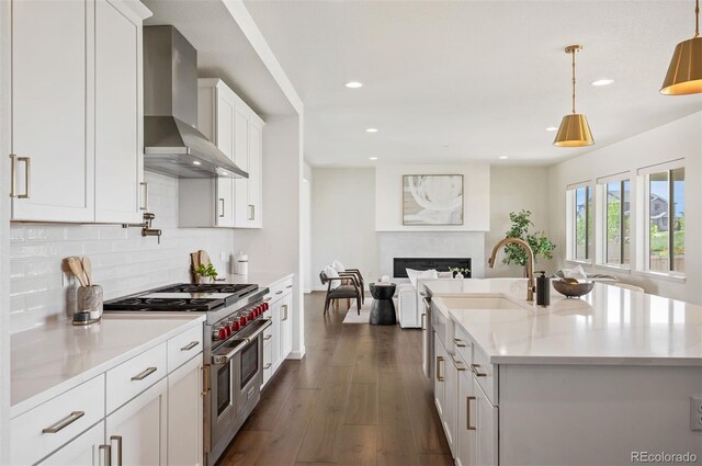 14391 Shasta Daisy Pt, Parker, CO 80134 - kitchen featuring double oven range, wall chimney exhaust hood, open floor plan, a sink, and dark wood-style flooring