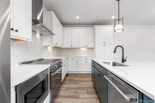 kitchen featuring sink, hardwood / wood-style flooring, wall chimney exhaust hood, decorative backsplash, and stainless steel appliances