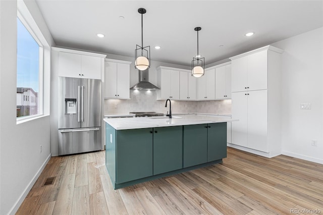 kitchen with refrigerator, white cabinets, light wood-type flooring, and backsplash