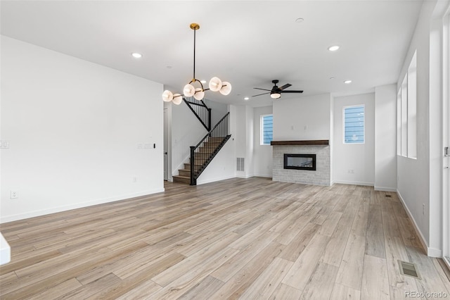 unfurnished living room featuring a fireplace, light hardwood / wood-style flooring, and ceiling fan