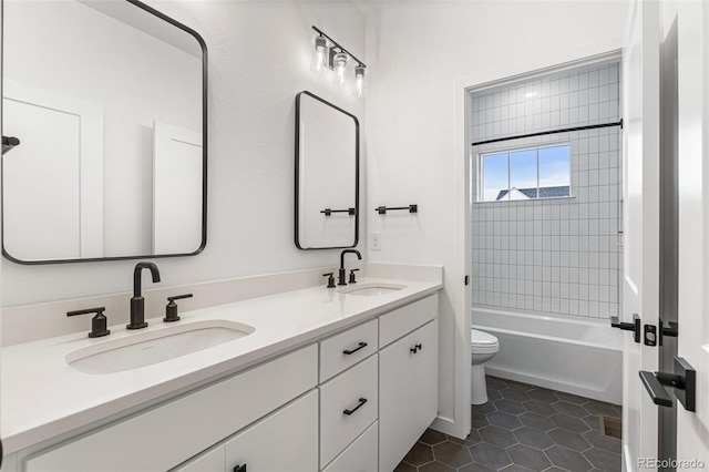 full bathroom featuring toilet, tiled shower / bath combo, dual bowl vanity, and tile patterned floors