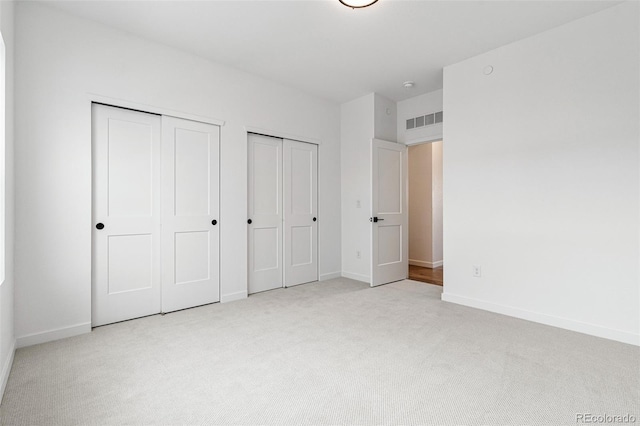 unfurnished bedroom with light carpet and two closets