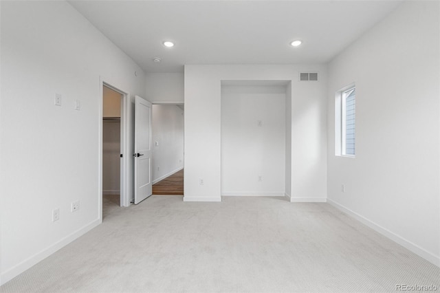 unfurnished bedroom with light colored carpet, a closet, and a walk in closet